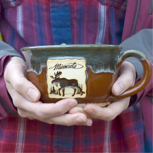 hands holding a handmade soup mug with logo