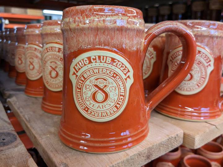 Orange clay beer stein with brewery logo.