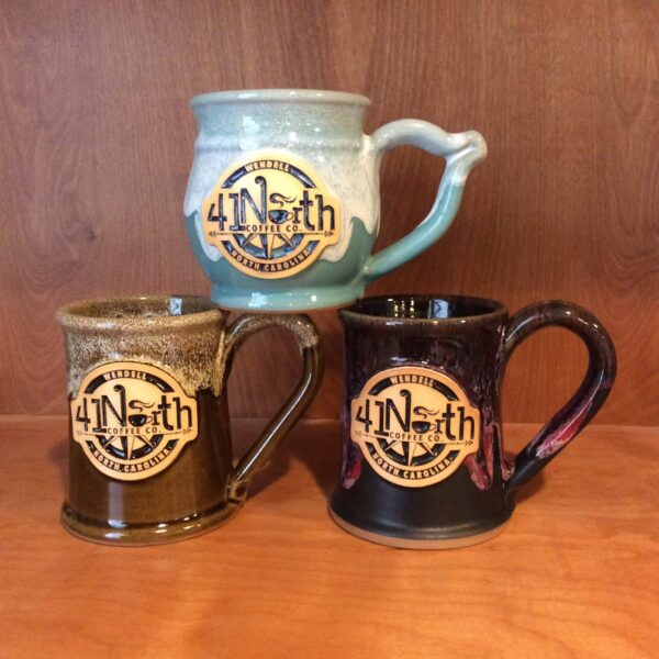 Stack of three coffee mugs with a clay logo medallion reading "41 North".