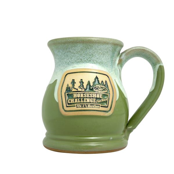 Green and white coffee mug with a clay logo medallion featuring the text "Horseshoe Challenge".