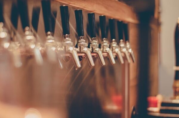 Row of beer taps with black handles.