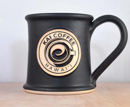 Black coffee mug with logo medallion with Text "Kai Coffee Hawai'i" with an overhead view of an illustration of a coffee mug.