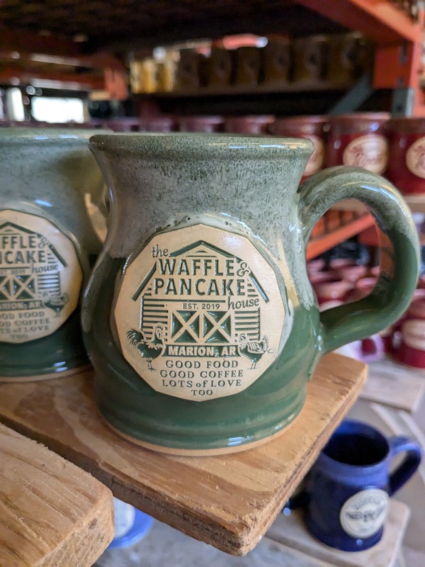 green and white coffee mug with logo of a pancake house