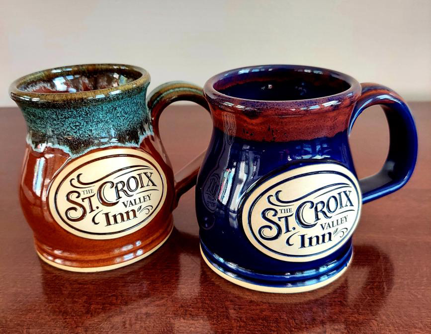 Two handmade custom coffee mugs on a table.