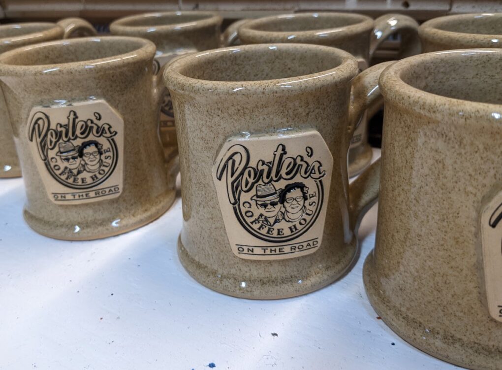 Tan glazed pottery mugs with company logo.