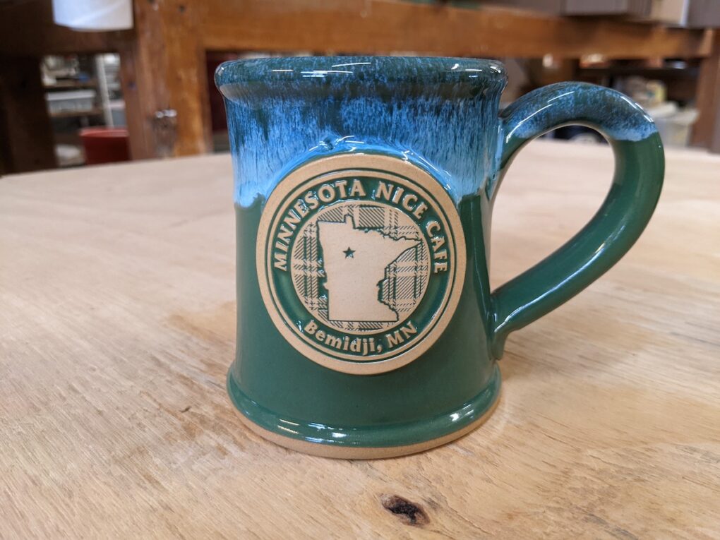 Image of state of Minnesota on a green and blue stoneware coffee mug.