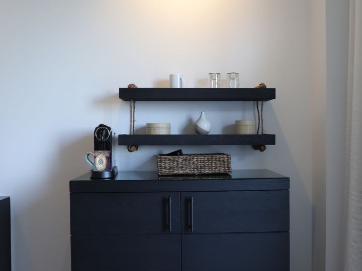 Cabinet with coffee maker and mugs on top of it.