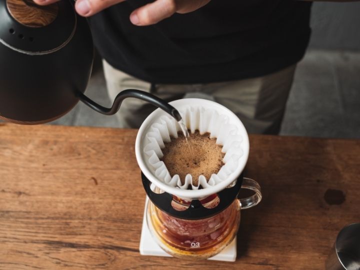 Person making coffee using a pour over method.