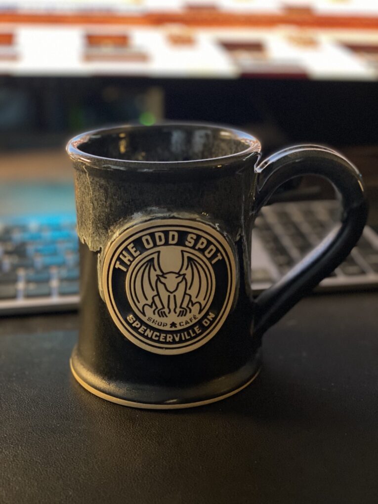 Black coffee mug with custom logo sitting in front of a keyboard.