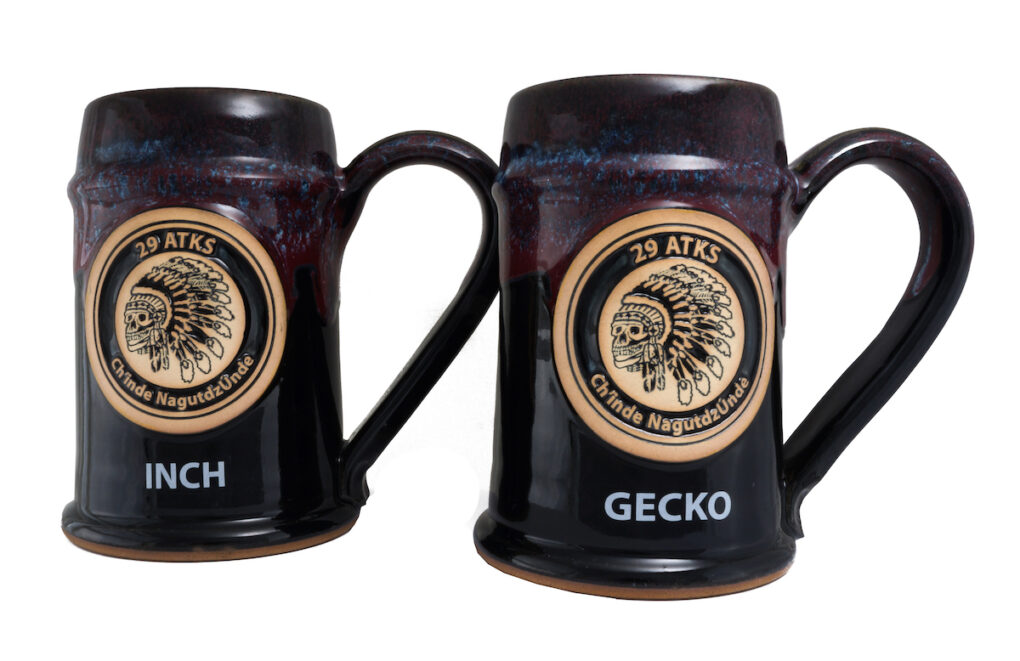 Two beer steins with military insignia and call names.