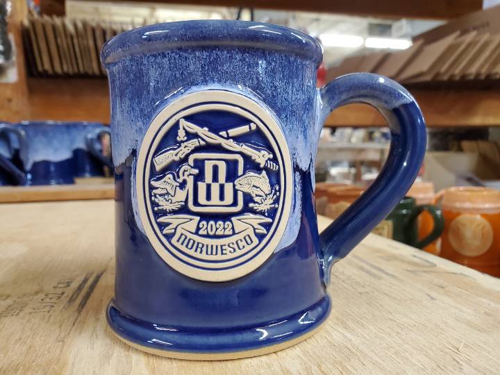 Blue coffee mug with clay medallion company logo.