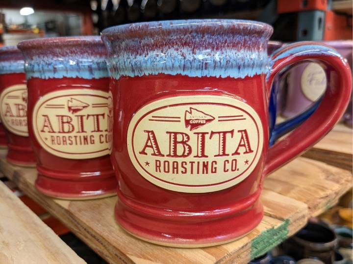 Red and blue coffee mug with text "Abita Roasting Co." on a clay logo medallion.