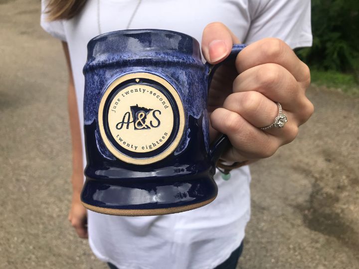 New bride holding a blue coffee mug as a personalized wedding favor for guests.