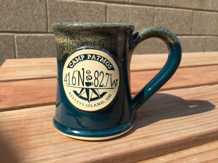 green coffee mug on a table with a summer camp logo