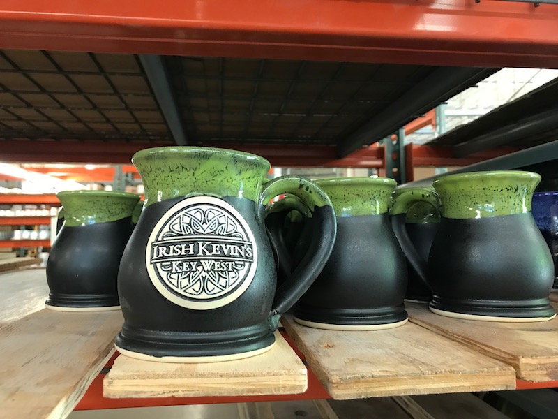 black mugs with green rims and a logo reading 'irish kevin's key west'.