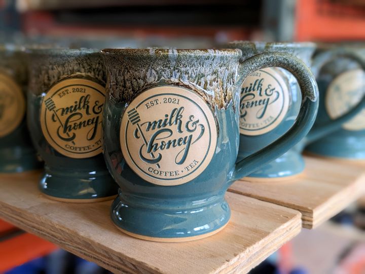 green coffee mug with a log for 'milk and honey coffee and tea' shop