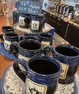 group of black and blue coffee mugs on a table with a for sale sign