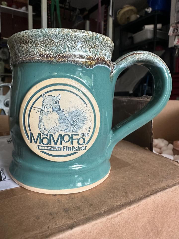 Teal coffee mug with clay medallion of a squirrel and text MoMoFo race