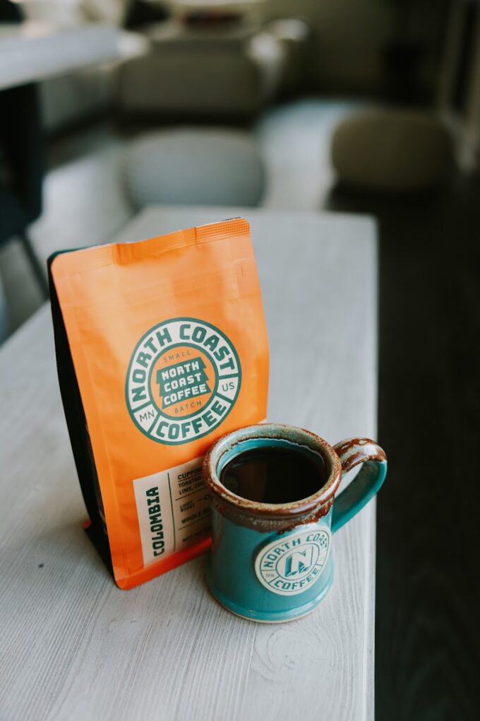 teal coffee mug next to a bag of coffee beans