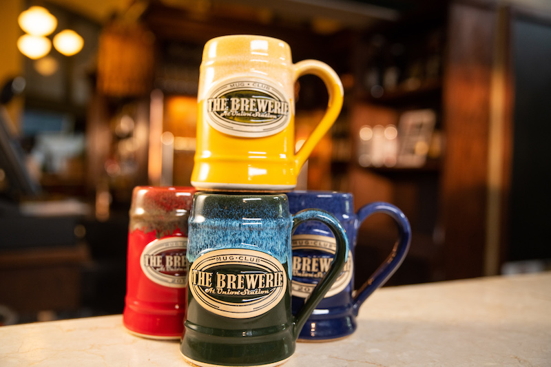 stack of beer steins with logos sitting on a bar