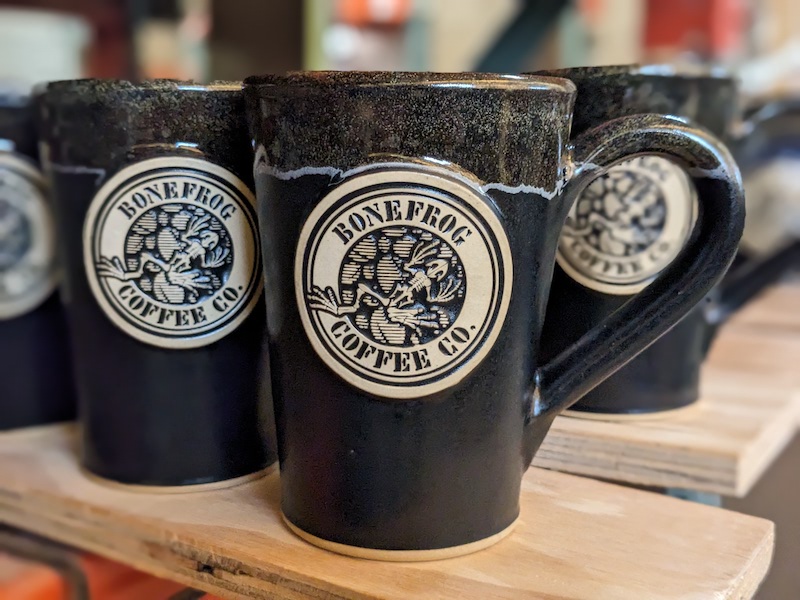 group of black wholesale coffee mugs with a coffee company logo