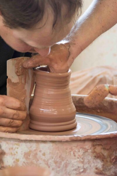 person make a clay mug on a pottery wheel