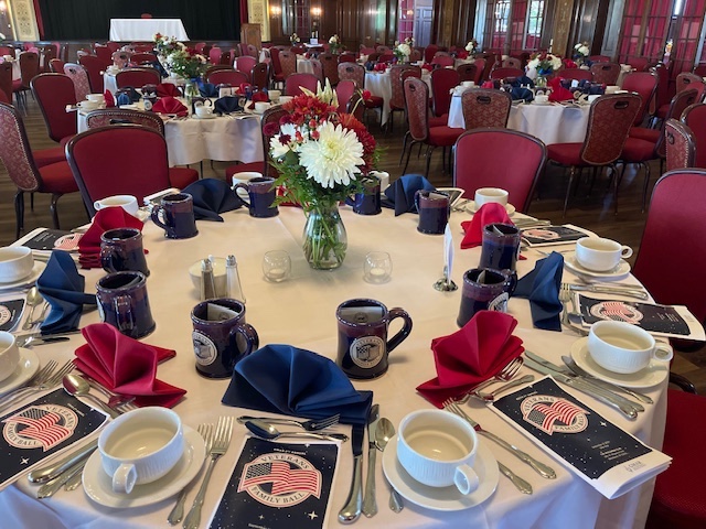 table at an event dressed with plates, mugs and napkins